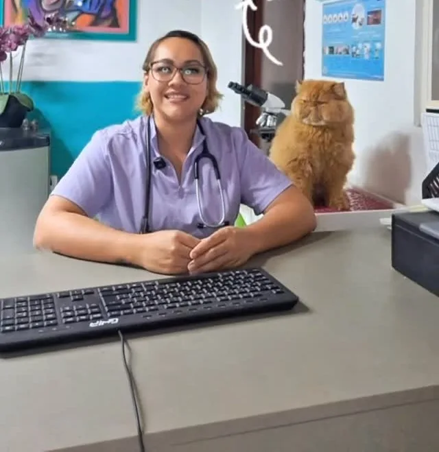 Veterinaria sonriendo en su consultorio de Wawao, con un gato persa a su lado